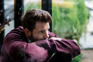 Man looking sad at a rainy window