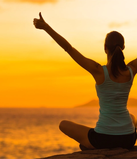 Woman giving thumbs up towards the ocean